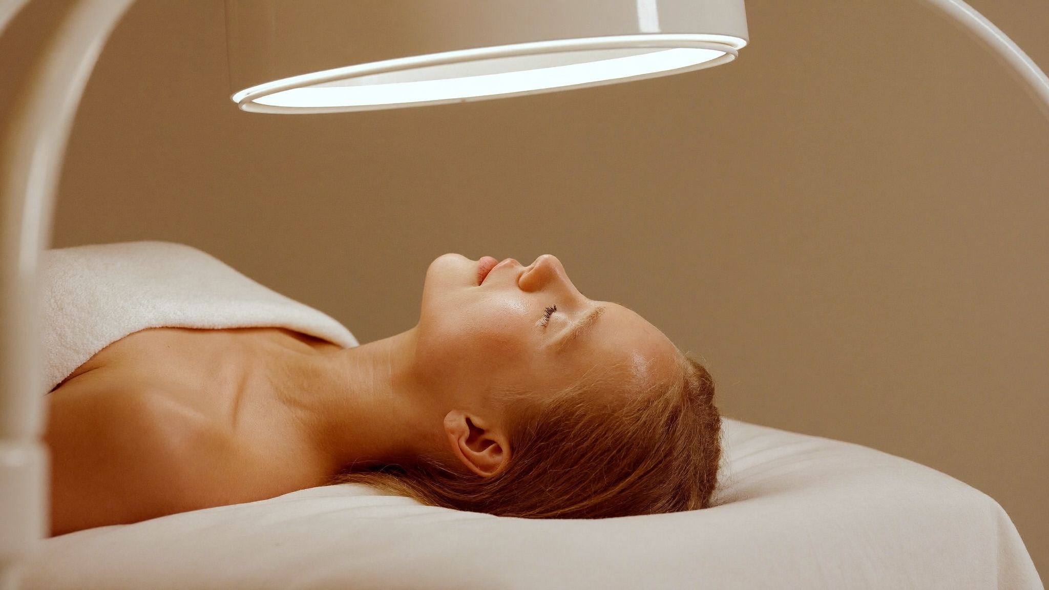Woman resting with her eyes closed under a soft treatment lamp