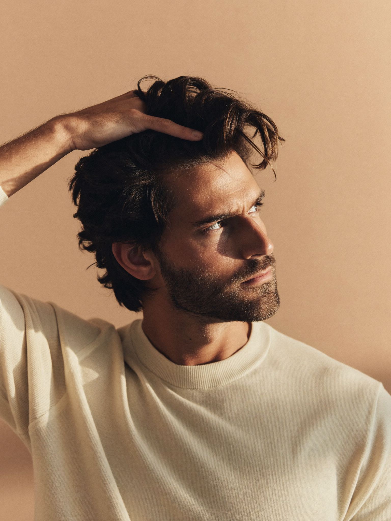 Man running his hand through thick dark hair