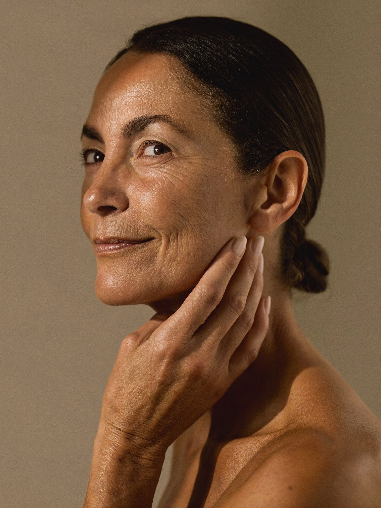 Smiling woman in her forties touching her jawline